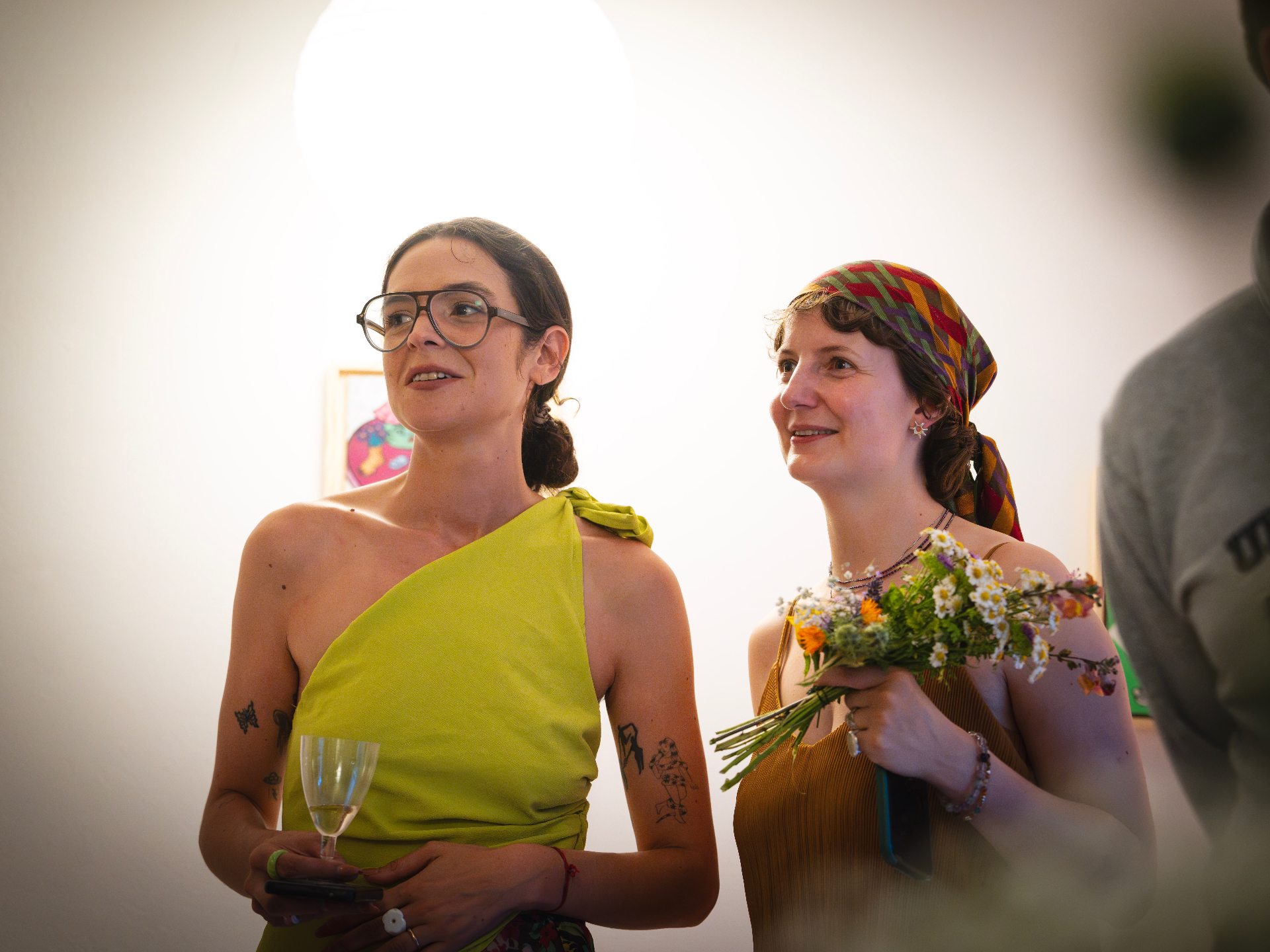 Two guests in conversation at the Seefeld Session, one holding a wildflower bouquet of chamomile and verbena