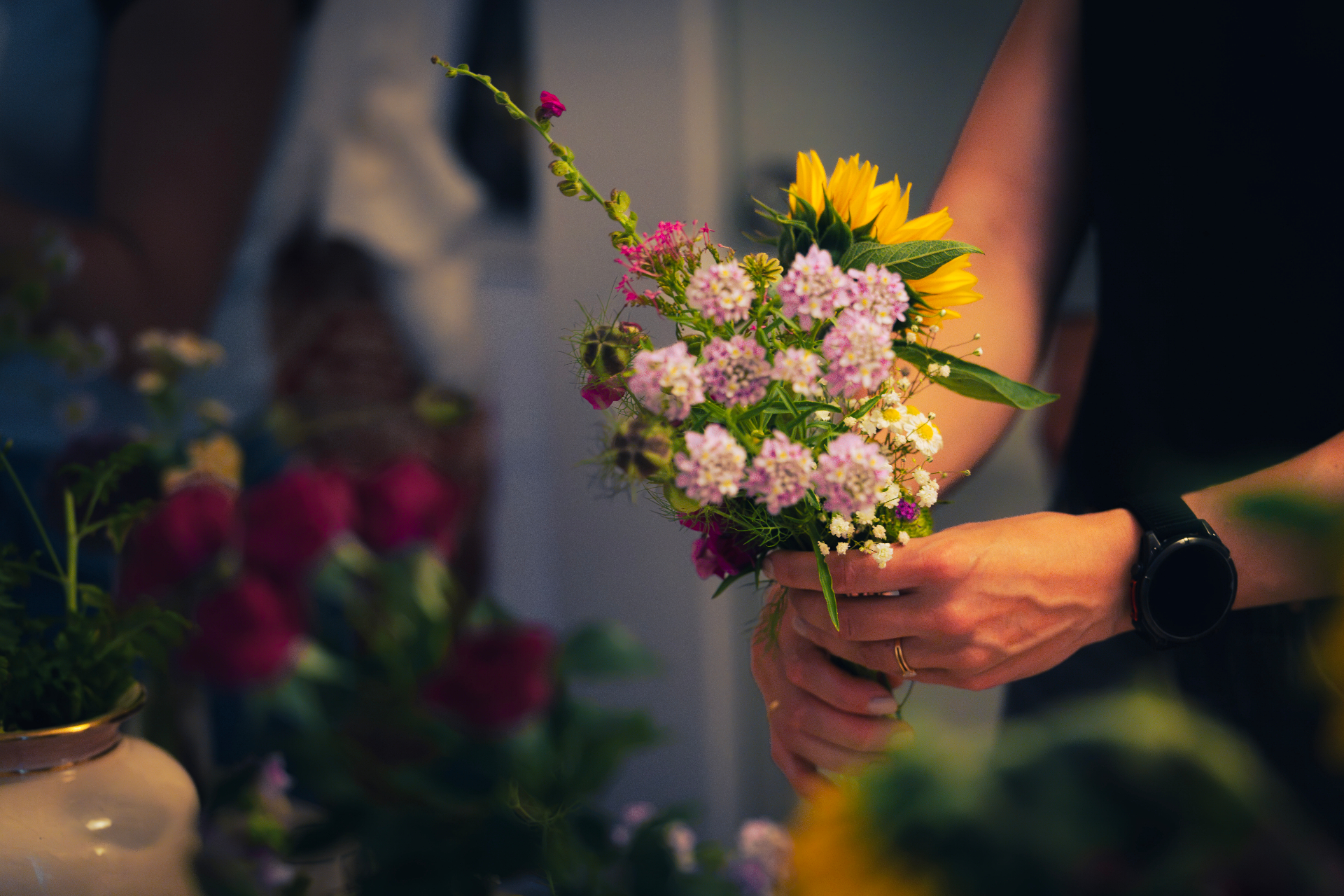 Hands holding a gathered bouquet with pale pink scabiosa, chamomile and sunflower at the Zurich Seefeld Session