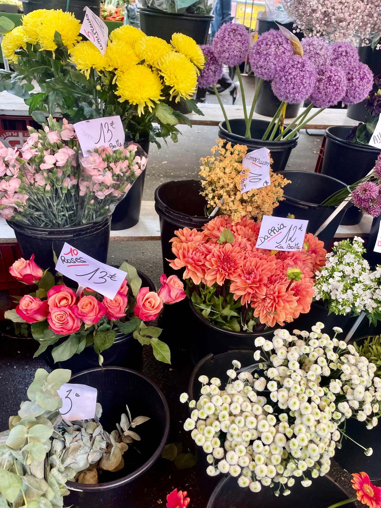 Parisian flower market stall with buckets of yellow chrysanthemums, allium, roses and dahlias with handwritten price tags