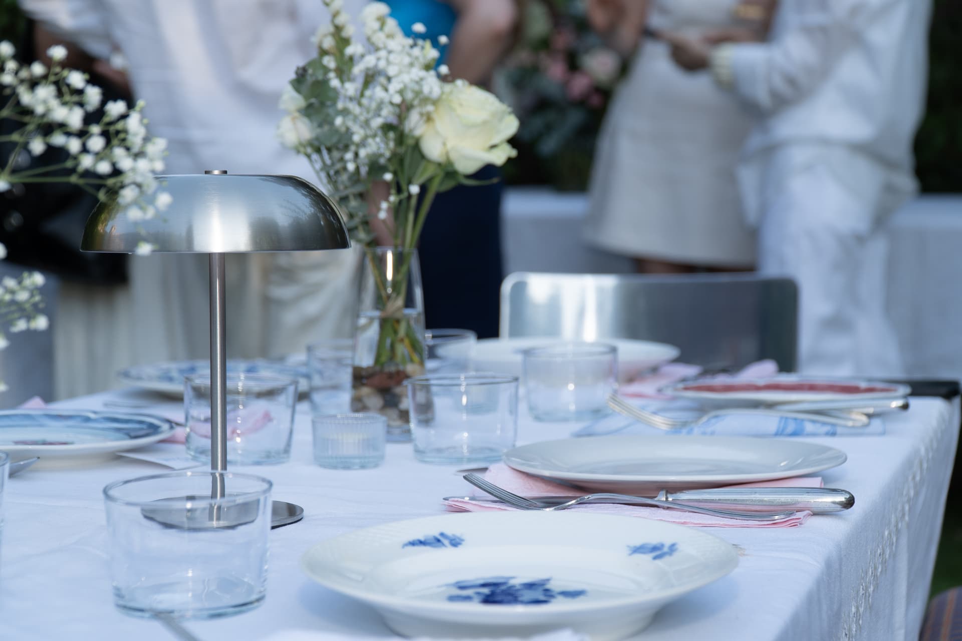 Long white table set with blue-and-white china, glassware and vases of white roses and gypsophila at the Madrid birthday celebration