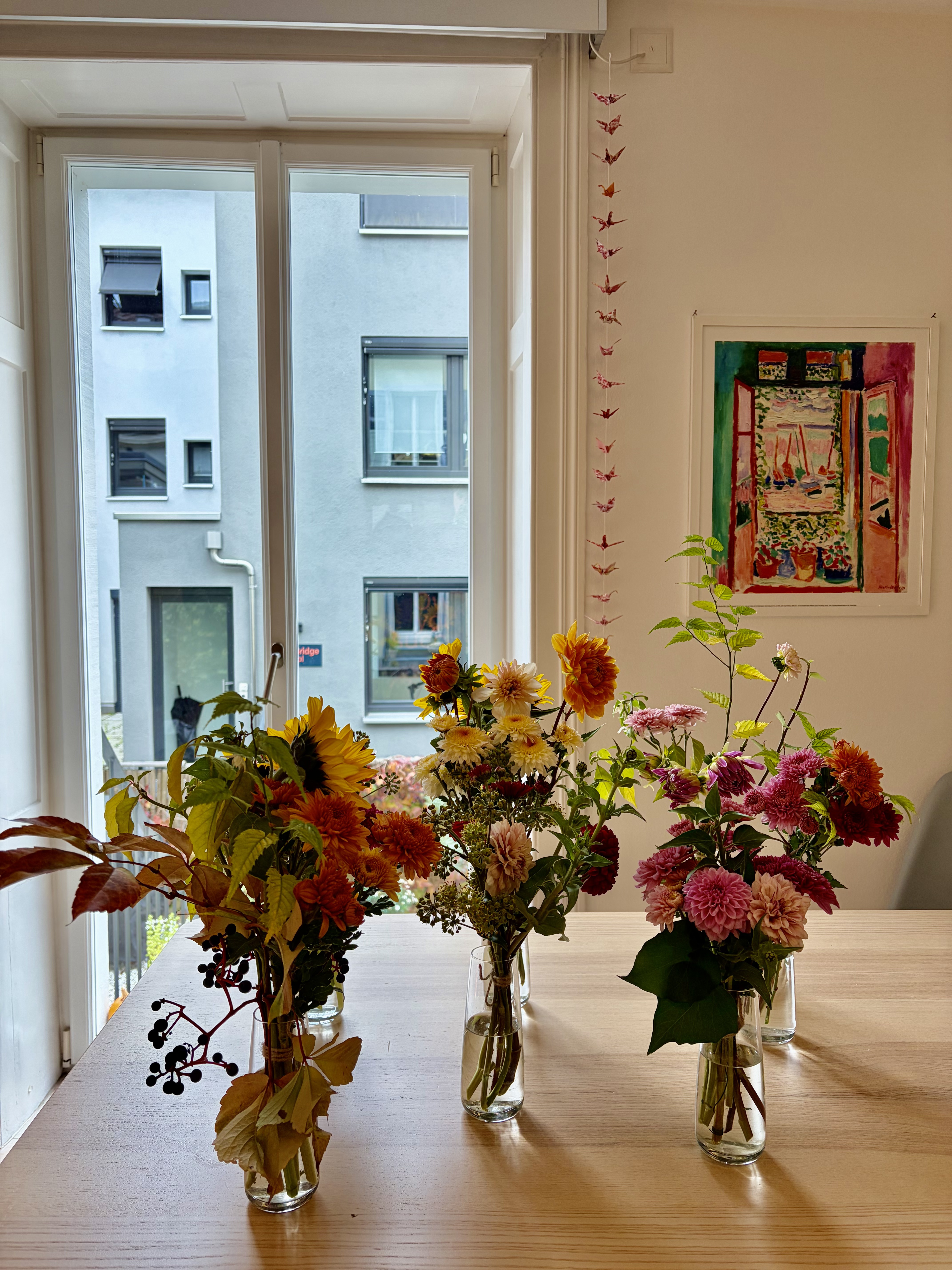 Autumn arrangements of dahlias, sunflowers and berries in glass vases by a bright window at the private birthday event