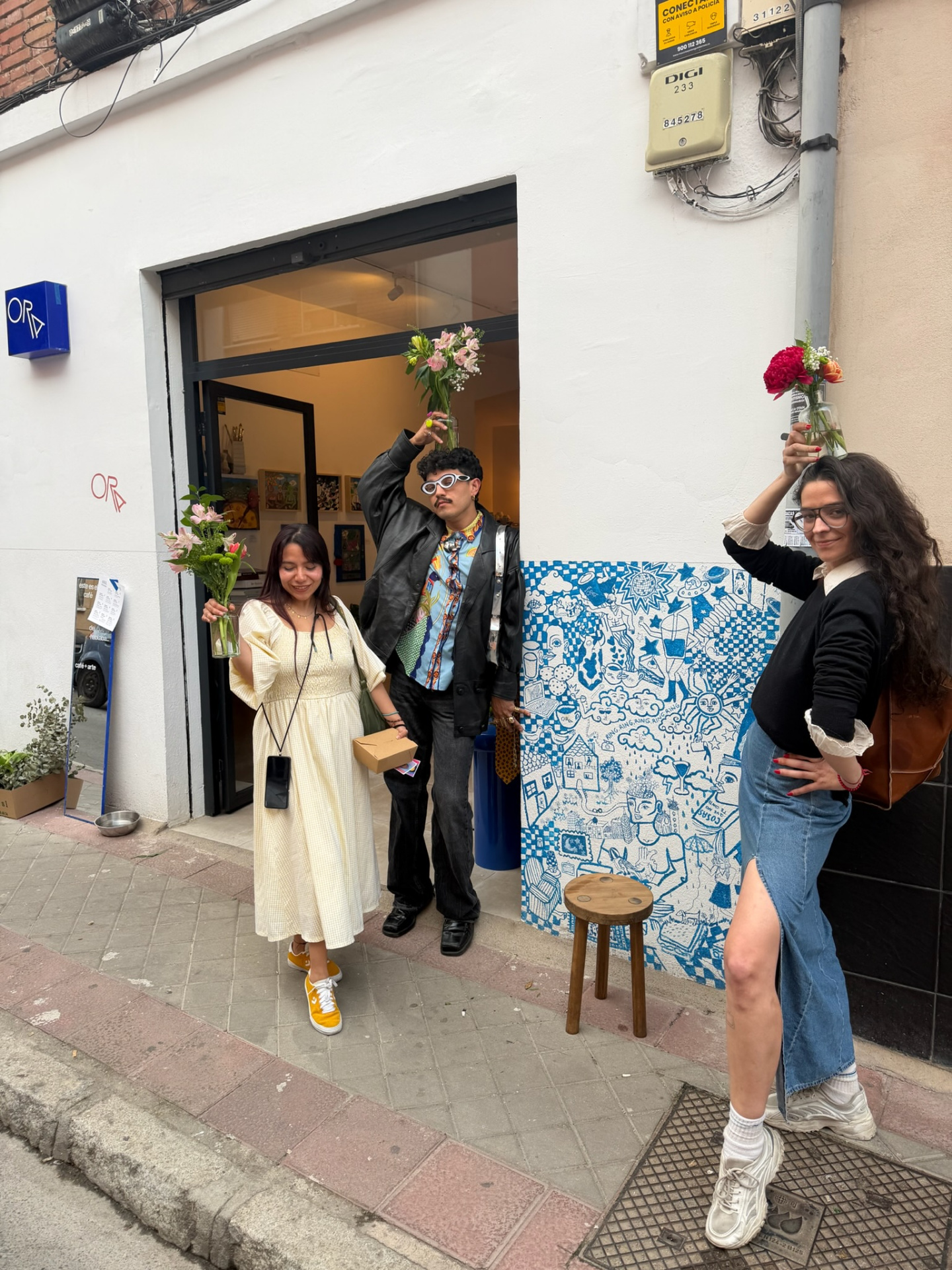 Three friends posing with bud vases outside the Madrid pop-up gallery