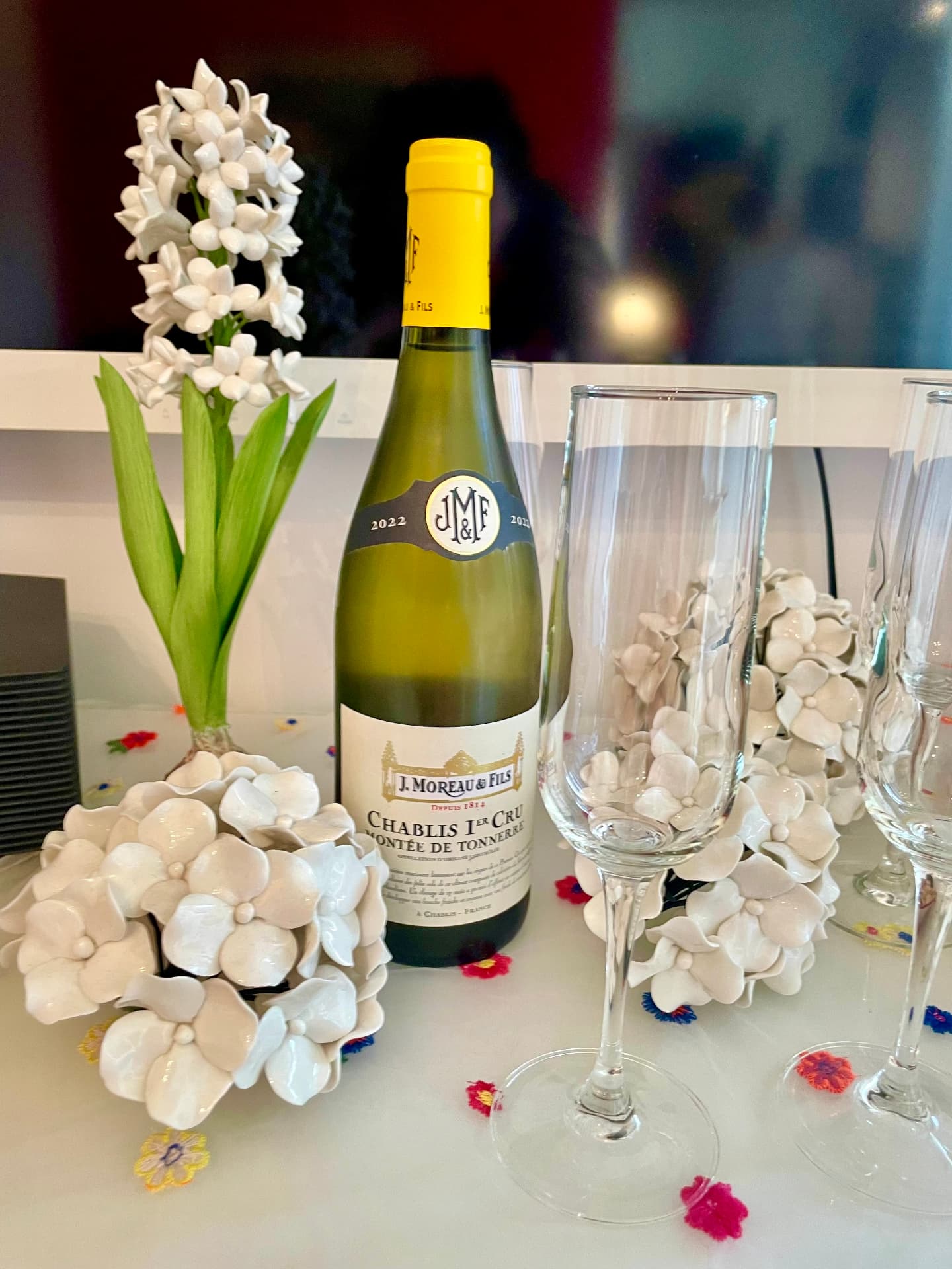 Bottle of Chablis 1er Cru with champagne flutes, ceramic hydrangeas and a white hyacinth