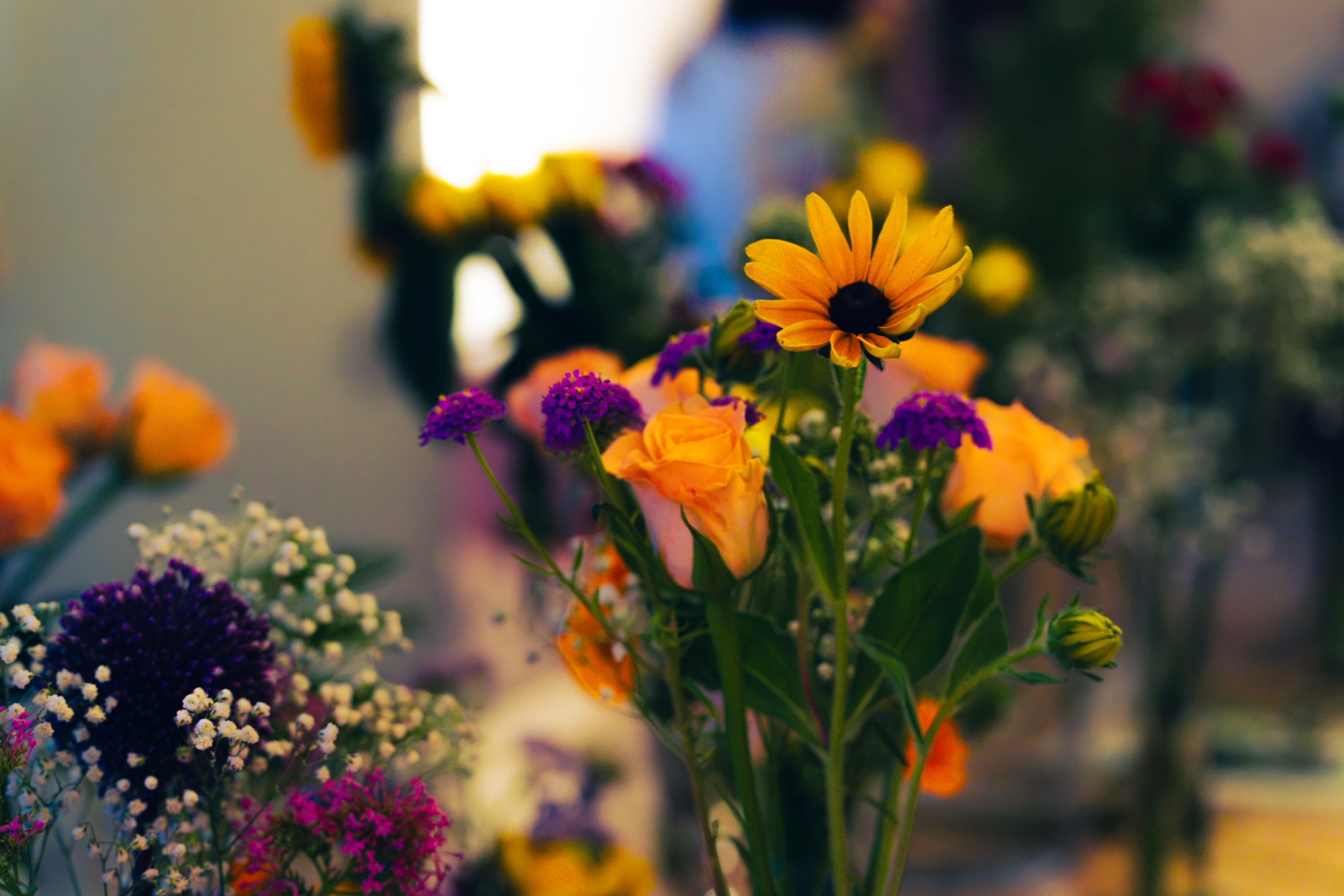 Row of colourful arrangements — rudbeckia, roses, verbena, gypsophila — lining the table at the Seefeld Session