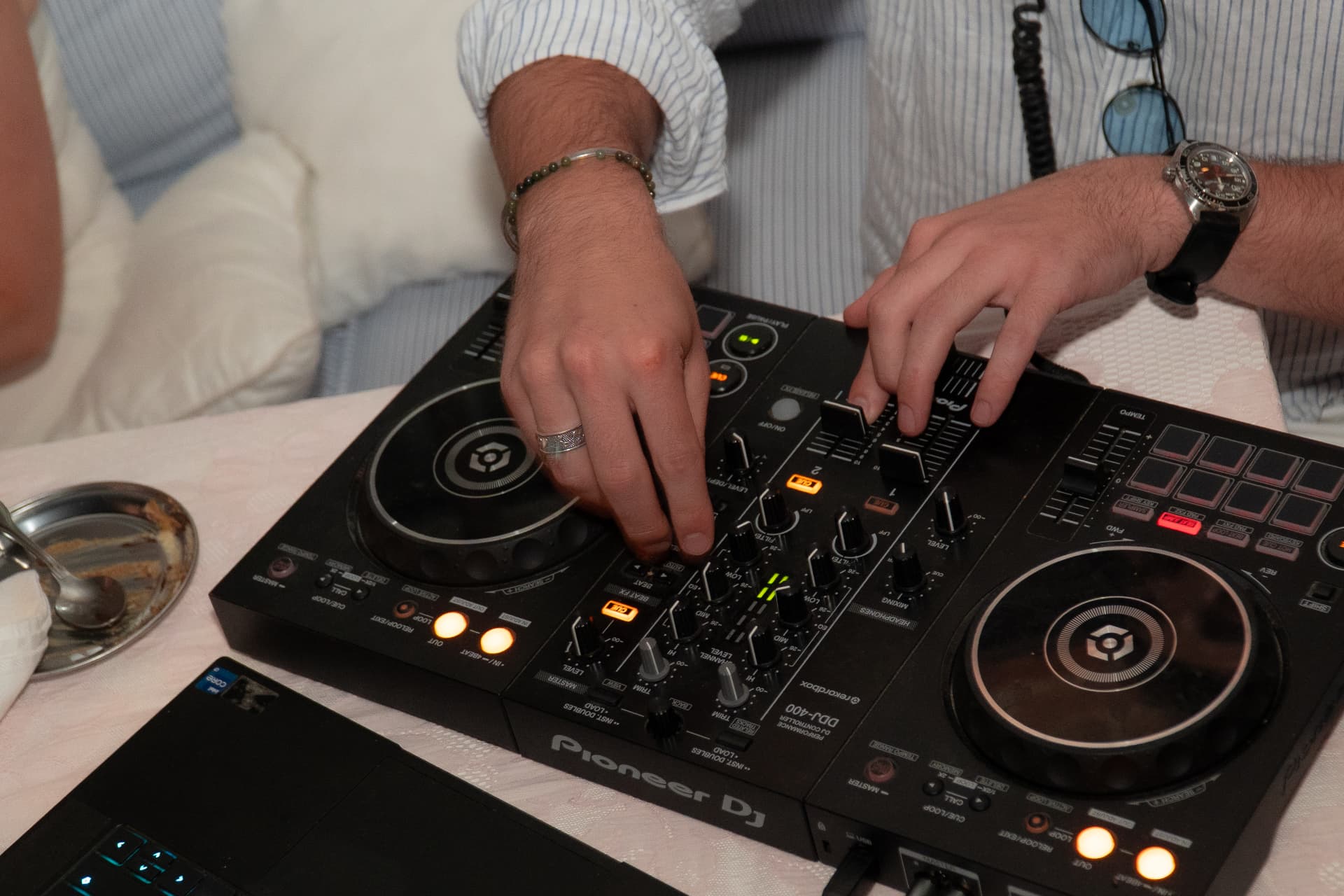 Hands mixing on a Pioneer DJ controller set up beside the dinner table